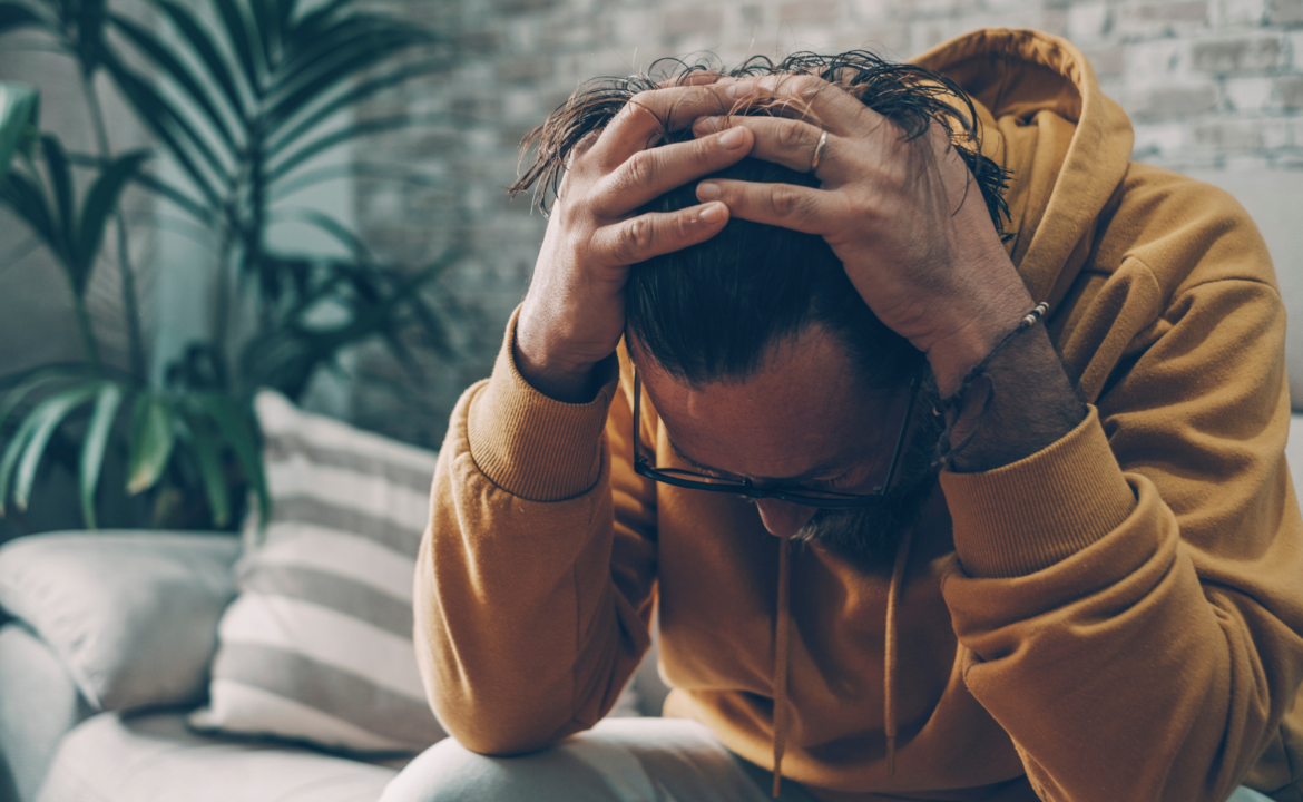 Man sitting quietly with hands clasped, reflecting the internal struggle of performance anxiety erectile dysfunction {{brizy_dc_image_alt entityId=